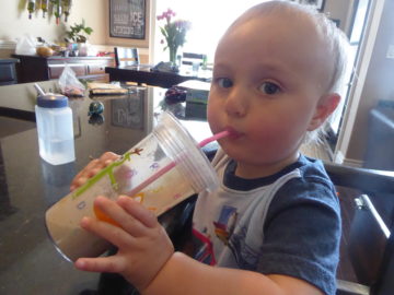 15 month old sipping a Chocolatey Almond Cacao Smoothie through a cup with a straw